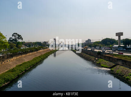 Landscape shot, river Tiete in Sao Paulo, Brazil, with traffic to the right and bridge in the distance Stock Photo