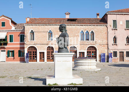 Statue of Baldassare Galuppi in Piazza Baldassare Galuppi, Burano, Venice, Veneto,  Italy, with the lace museum and ancient well head behind. Stock Photo