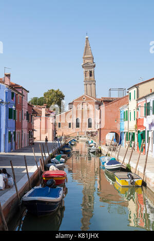 San Martino Church with its leaning bell tower, Burano, Venice, Italy reflected in the tranquil water of the canal below Stock Photo