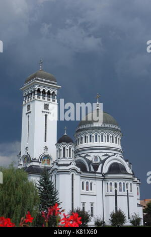 Holy Trinity Church with romanian flag and cloudy sky. Sighisoara, Transylvania, Romania Stock Photo