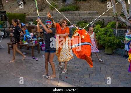 girl, hitting a pinata, pinata filled with candy sweets and toys, birthday party, Castro Valley, Alameda County, California, United States Stock Photo