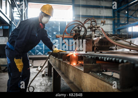 Asian worker using CNC plasma cutter Stock Photo