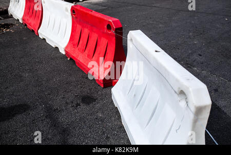 Red and white plastic barriers blocking the asphalt road Stock Photo