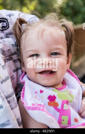 Happy nine month old girl as she eats soft apple chunks outside Stock Photo