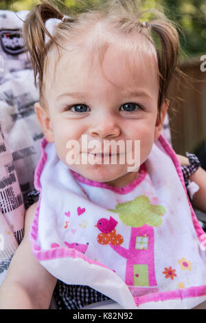 Happy nine month old girl as she eats soft apple chunks outside Stock Photo