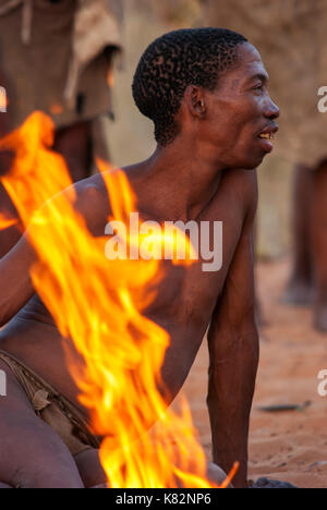 Ju/'Hoansi or San bushmen hunter gathering around camp fire at their village, Grashoek. They are members of various indigenous hunter-gatherer people  Stock Photo