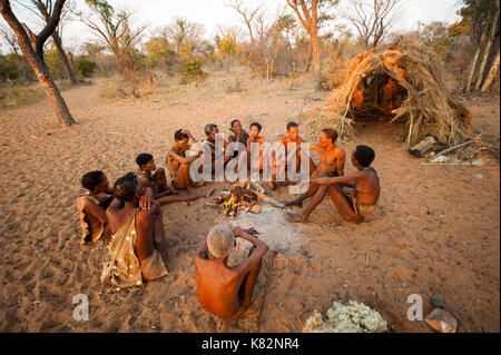 Ju/'Hoansi or San bushmen hunter gathering around camp fire at their village, Grashoek. They are members of various indigenous hunter-gatherer people  Stock Photo