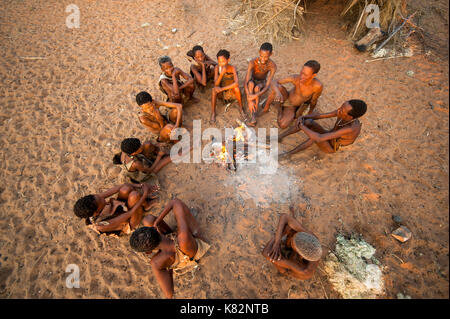 Ju/'Hoansi or San bushmen hunter gathering around camp fire at their village, Grashoek. They are members of various indigenous hunter-gatherer people  Stock Photo