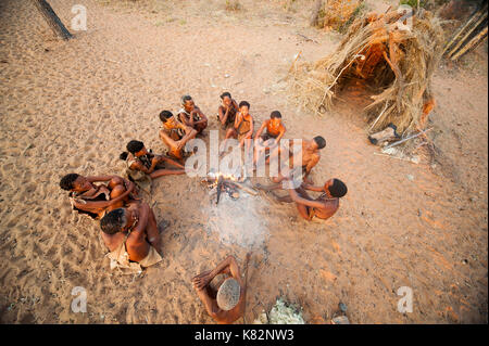 Ju/'Hoansi or San bushmen hunter gathering around camp fire at their village, Grashoek. They are members of various indigenous hunter-gatherer people  Stock Photo