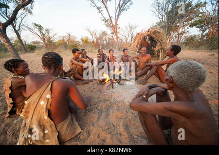 Ju/'Hoansi or San bushmen hunter gathering around camp fire at their village, Grashoek. They are members of various indigenous hunter-gatherer people  Stock Photo