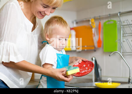 Mother And Kid Son Washing Dishes Together Stock Photo