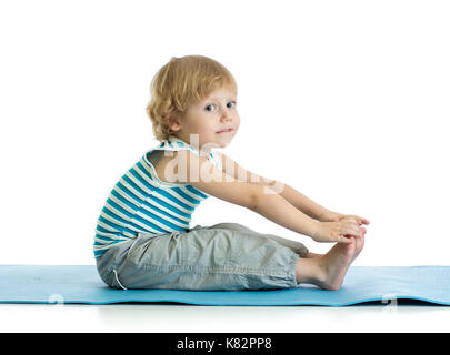 Child boy practicing yoga, stretching in exercise wearing sportswear. Kid isolated over white background Stock Photo