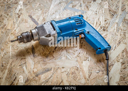 Blue old drill-screwdriver close-up on a wooden surface. Stock Photo
