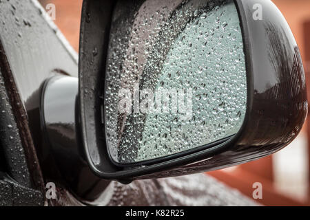 Car mirror in raindrops close-up. Stock Photo