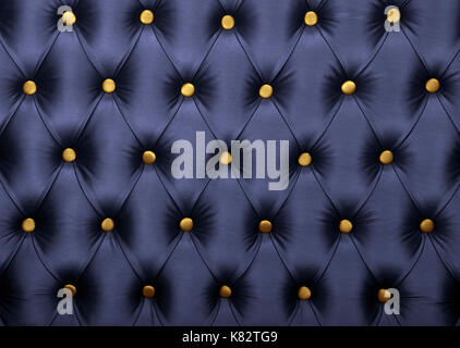 Dark blue capitone textile background with golden yellow buttons, retro Chesterfield style soft tufted fabric furniture upholstery diamond pattern dec Stock Photo