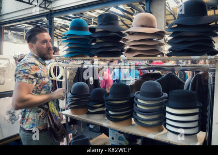 MILAN, ITALY - SEPTEMBER 17, 2017: hipster young man looking hats at East Market grand opening, the first marketplace in Milan where everyone can buy, Stock Photo