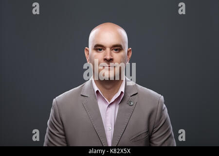 Portrait of a bald affable man in a suit against a dark background, studio shot. Stock Photo