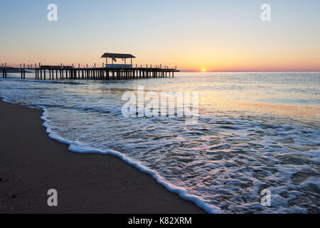 gazebo on the wooden pier into the sea with the sun at sunset Stock Photo