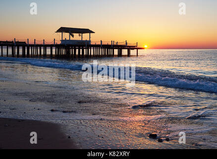 gazebo on the wooden pier into the sea with the sun at sunset Stock Photo