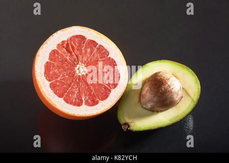 Fresh and juicy grapefruit and avocado isolated on a black background. Stock Photo