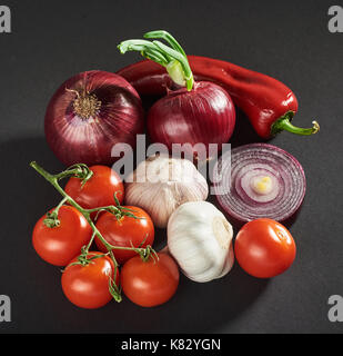 onion and garlic and hot peppers and tomatoes isolated on a black background. Stock Photo