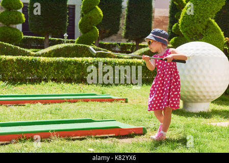 Child playing mini - golf on artificial grass. Stock Photo