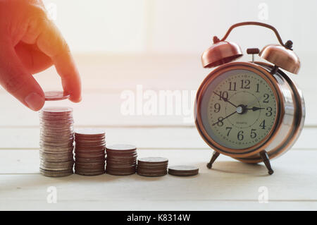 hand put money on  pile of coins,  concept in growth, save and investment in business Stock Photo