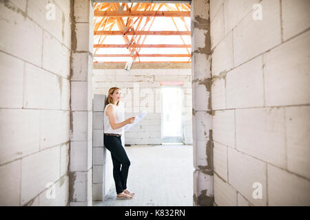 Architect at the construction site looking at blueprints. Stock Photo