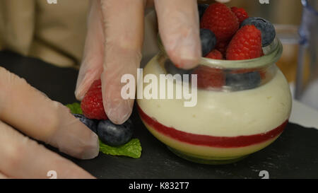 Female hands are adorned with berries. Hand putting Strawberry in Yogurt, close up Stock Photo