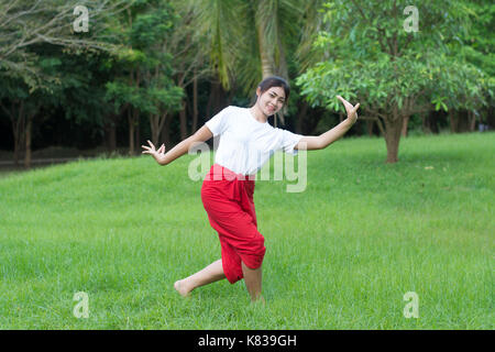 Asian young girl learning Thai dance. Classical Dance in white shirt red loincloth, Demonstrate dance in the garden Stock Photo