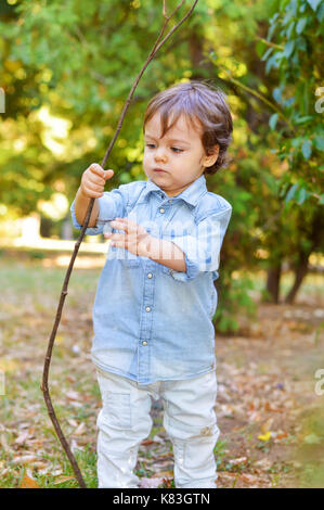 Adorable one year old playing with wooden branch Stock Photo