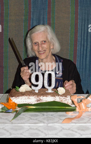 Grandma celebrating her 90th birthday and cuting the cake Stock Photo