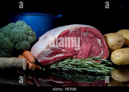 Raw rib of Beef with seasonal vegetables fresh horseradish and rosemary against a black background Stock Photo