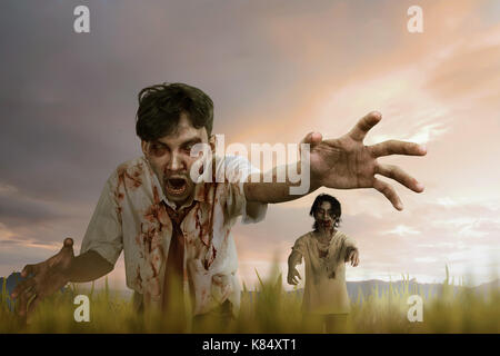 Two asian zombie man with mad face and dirty hand standing against dramatic sky background Stock Photo