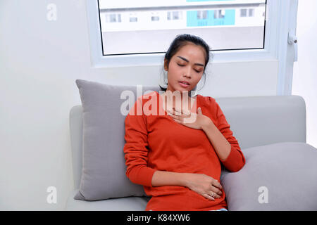 Young asian woman feeling pain in her chest at home Stock Photo