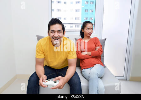 Portrait of bored asian woman while her boyfriend playing video games at home Stock Photo