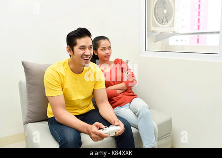 Portrait of bored asian woman while her boyfriend playing video games at home Stock Photo