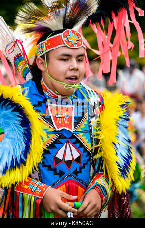 First Nations teenager boy fancy dancer dressed with colourful regalia to perform the grass dance during a Pow Wow in London, Ontario, Canada. Stock Photo