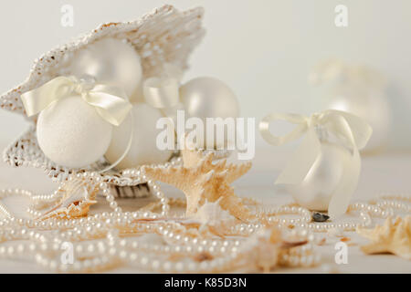 Christmas and New Year. Christmas-tree white toys in a marine style, seashells stones and starfish. Selective focus. Stock Photo