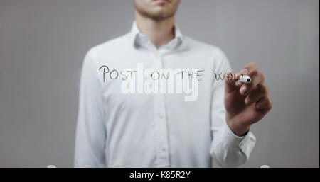Post on the wall, Man Writing on Glass Stock Photo