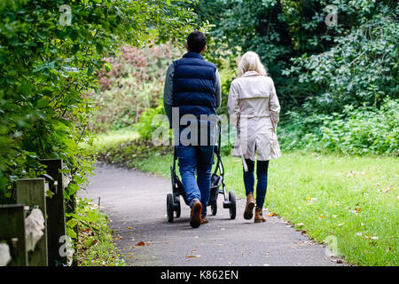 Summers Road, Godalming. 18th September 2017. UK Weather. Cloud cover began to clear this morning over the Home Counties, although the northerly wind meant a distinctly Autumnal feel to the weather. A couple walking their child around Broadwater Lake in Godalming, Surrey. Credit: james jagger/Alamy Live News Stock Photo