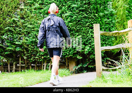 Summers Road, Godalming. 18th September 2017. UK Weather. Cloud cover began to clear this morning over the Home Counties, although the northerly wind meant a distinctly Autumnal feel to the weather. A power walker at Broadwater Lake in Godalming, Surrey. Credit: james jagger/Alamy Live News Stock Photo