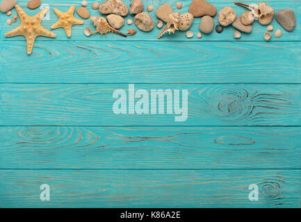 Border with rope, stones, sea shells and starfish on a turquoise wooden background. Top view. Stock Photo
