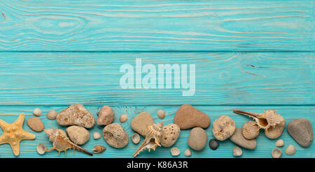 Border with rope, stones, sea shells and starfish on a turquoise wooden background. Top view. Stock Photo