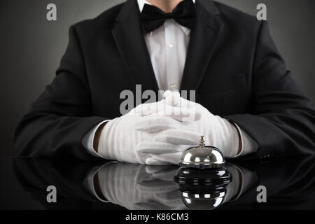 Close-up Of Waiter Sitting At Desk With Service Bell Stock Photo