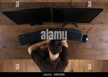 Man Sleeping At Desk With Computers Showing Program Code Stock Photo