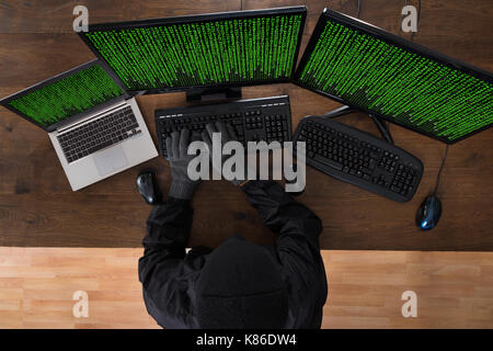 High Angle View Of Robber Hacking Computers And Laptop In Office Stock Photo
