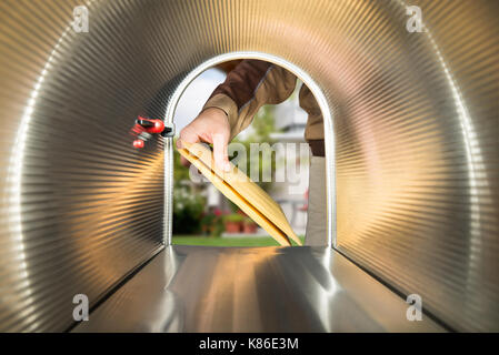 Close-up Of Postman Hands Putting Letters View From Inside The Mailbox Stock Photo