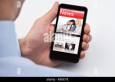 Close-up Of Businessperson Reading Online News On Mobile Phone Stock Photo