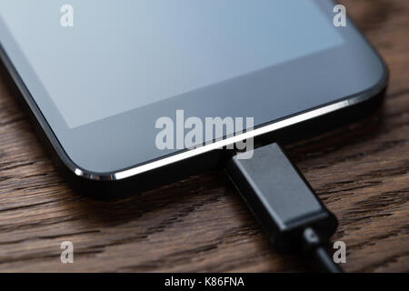 High angle view of smart phone connected to charger on table Stock Photo